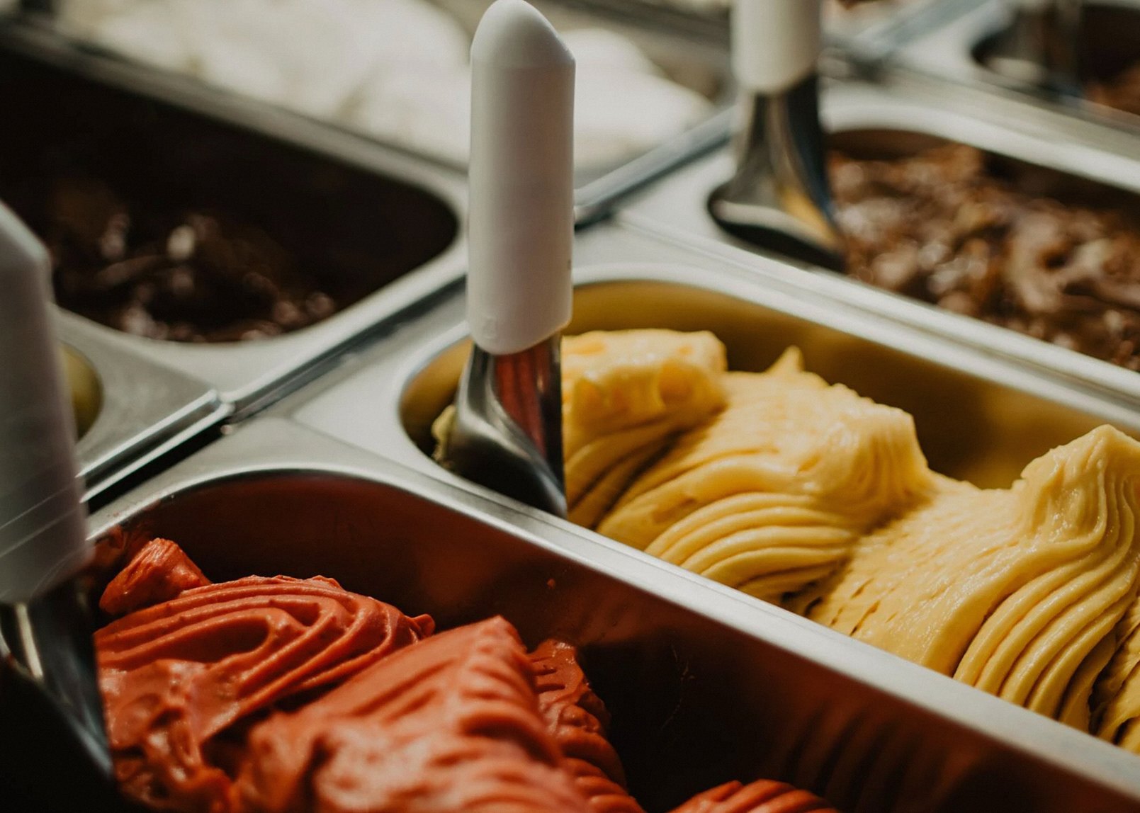 A vibrant display of colorful gelato flavors in metal trays at an ice cream shop.